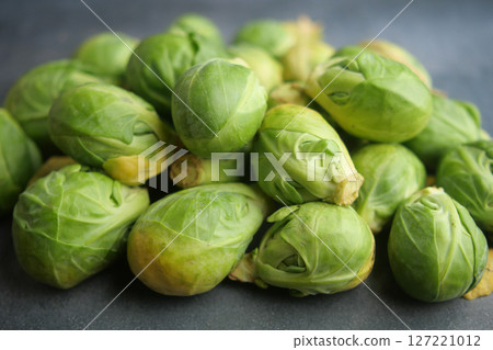 A Fresh Pile of Brussels Sprouts Resting on a Dark Surface Background A Fresh Pile of Brussels Sprouts Resting on a Dark Surface Background 127221012