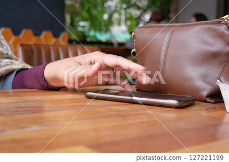 A hand grabbing and picking up mobile phone on the table. A hand grabbing and picking up mobile phone on the table. 127221199