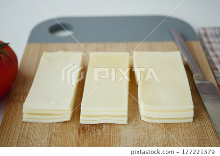 Deliciously Sliced Cheese Displayed Beautifully on a Wooden Cutting Board Deliciously Sliced Cheese Displayed Beautifully on a Wooden Cutting Board 127221379