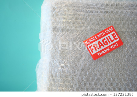 A cardboard box marked with a caution label for fragile goods handling during shipping A cardboard box marked with a caution label for fragile goods handling during shipping 127221395