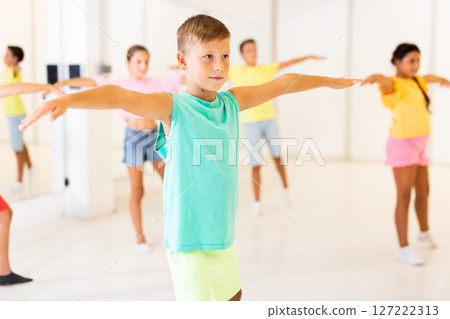 Preteen boy doing stretching workout before training in choreography class Preteen boy doing stretching workout before training in choreography class 127222313