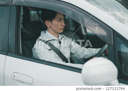 A man wearing work clothes and a tie travels by car 127222764