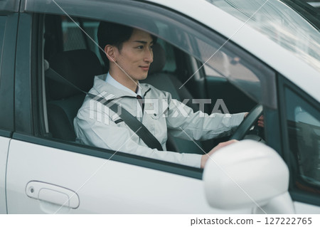 A man wearing work clothes and a tie travels by car 127222765