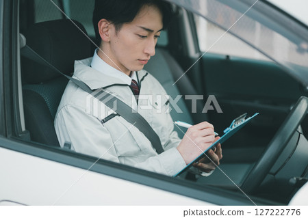 A man wearing work clothes and a tie making a rounds in a car A man wearing work clothes and a tie making a rounds in a car 127222776