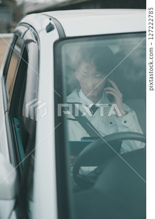 一名身穿工作服、打著領帶的男子正在車上打電話 127222785