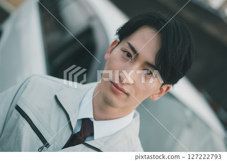 A man wearing work clothes and a tie and a company car A man wearing work clothes and a tie and a company car 127222793