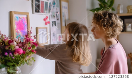Child and mother engaging in creative art display in a cozy home environment 127223268