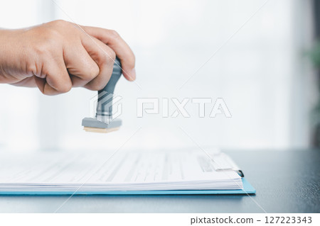 Businessman hands stamp approve on financial business approval document paper. Man hand accepted permit contract agreement. Broker manager sign contract bank guarantee approved stamp application form Businessman hands stamp approve on financial business approval document paper. Man hand accepted permit contract agreement. Broker manager sign contract bank guarantee approved stamp application form 127223343