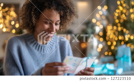 Individual enjoys receiving a heartfelt card during a festive indoor gathering in a cozy setting with holiday decorations 127223510