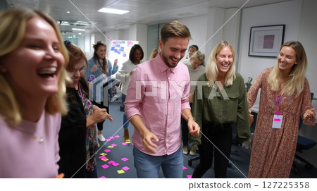 Team members engaged in laughter and fun during a collaborative activity in an office setting 127225358
