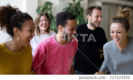 Group of friends enjoying a joyful moment together in a bright, modern indoor space during a casual gathering 127225430
