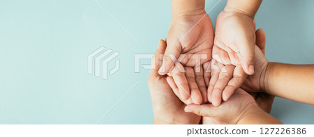 Close-up top view of family hands stack isolated background. Parents and kid hold empty space signifying support and love on Family and Parents Day. Close-up top view of family hands stack isolated background. Parents and kid hold empty space signifying support and love on Family and Parents Day. 127226386