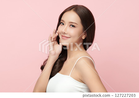 A beautiful young Asian woman with clean, fresh skin against a pink background. Skincare, facial treatment, cosmetology, beauty, and spa. An elegant portrait of an Asian woman. A beautiful young Asian woman with clean, fresh skin against a pink background. Skincare, facial treatment, cosmetology, beauty, and spa. An elegant portrait of an Asian woman. 127227203