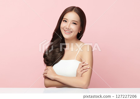 A beautiful young Asian woman with clean, fresh skin against a pink background. Skincare, facial treatment, cosmetology, beauty, and spa. An elegant portrait of an Asian woman. 127227206