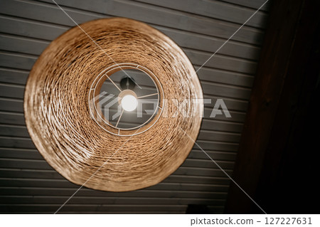 Wicker Pendant Lamp Hanging from Wooden Ceiling 127227631