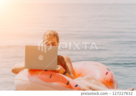 Woman Laptop Beach Working Remotely on Inflatable Float 127227632