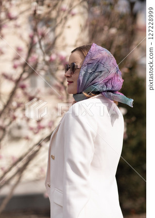 Headscarf woman magnolia, daytime outdoors for a spring stroll in a white blazer. Headscarf woman magnolia, daytime outdoors for a spring stroll in a white blazer. 127228999