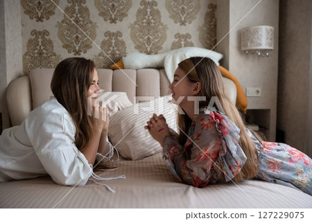 Mother Daughter Bedroom Bonding: Affectionate women lying bed, sharing intimate moment, home. Mother Daughter Bedroom Bonding: Affectionate women lying bed, sharing intimate moment, home. 127229075
