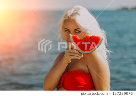 Watermelon Beach Summer: Woman enjoys refreshing watermelon slice near ocean, sunny day. Watermelon Beach Summer: Woman enjoys refreshing watermelon slice near ocean, sunny day. 127229076