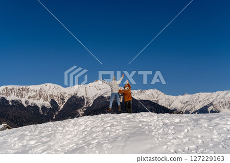 Mountains Snow Peak: Hikers celebrating scenic winter view atop snowy mountain range. Mountains Snow Peak: Hikers celebrating scenic winter view atop snowy mountain range. 127229163