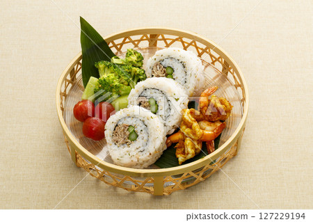 Japanese-style plate of ginger-fried sushi rolls and colorful side dishes 127229194