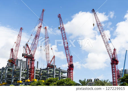 Low-angle view of cranes and steel structures of building construction with a blue sky background in Taiwan. Low-angle view of cranes and steel structures of building construction with a blue sky background in Taiwan. 127229915