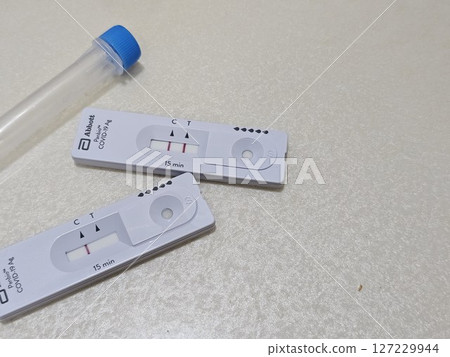 快速抗原檢測盒附有控制線和檢測線,旁邊是中性背景上的無菌鼻拭子,展示了在家中進行 COVID-19 快速抗原檢測盒附有控制線和檢測線,旁邊是中性背景上的無菌鼻拭子,展示了在家中進行 COVID-19 127229944