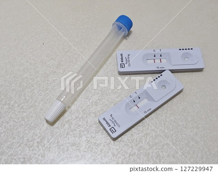 快速抗原檢測盒附有控制線和檢測線,旁邊是中性背景上的無菌鼻拭子,展示了在家中進行 COVID-19 快速抗原檢測盒附有控制線和檢測線,旁邊是中性背景上的無菌鼻拭子,展示了在家中進行 COVID-19 127229947