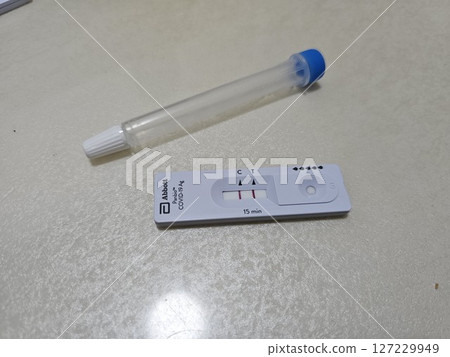 快速抗原檢測盒附有控制線和檢測線,旁邊是中性背景上的無菌鼻拭子,展示了在家中進行 COVID-19 快速抗原檢測盒附有控制線和檢測線,旁邊是中性背景上的無菌鼻拭子,展示了在家中進行 COVID-19 127229949