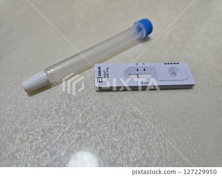快速抗原檢測盒附有控制線和檢測線,旁邊是中性背景上的無菌鼻拭子,展示了在家中進行 COVID-19 快速抗原檢測盒附有控制線和檢測線,旁邊是中性背景上的無菌鼻拭子,展示了在家中進行 COVID-19 127229950