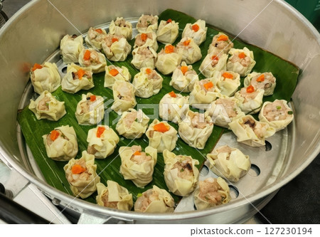 Steamed Dumplings in a Bamboo Steamer with Green Leaves Display Steamed Dumplings in a Bamboo Steamer with Green Leaves Display 127230194