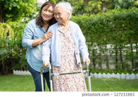 Doctor caregiver help and care Asian senior woman patient walk with walker in park at hospital. Doctor caregiver help and care Asian senior woman patient walk with walker in park at hospital. 127231661