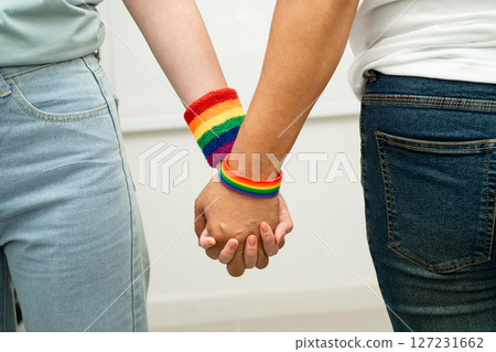 Asian LGBT couple woman holding hand wearing rainbow wristband. Asian LGBT couple woman holding hand wearing rainbow wristband. 127231662