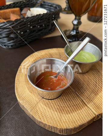 Tomato, green sauce for fried meat in metal sauce boats. Food on wooden stand. 127231671