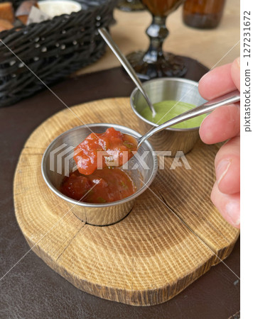 Tomato, green sauce for fried meat in metal sauce boats. Food on wooden stand. 127231672