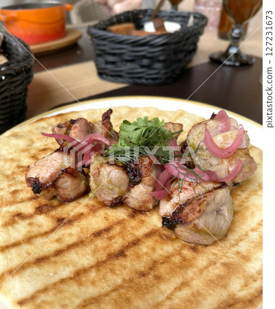 Chunks of grilled meat with pickled onions on pancake, pita. Asian traditional cuisine. Food and products. 127231673