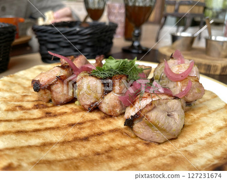 Chunks of grilled meat with pickled onions on pancake, pita. Asian traditional cuisine. Food and products. 127231674