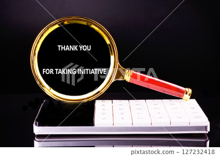 A magnifying glass with a red handle focuses on a thank you message placed above a digital calculator. This setup showcases appreciation for initiative taken A magnifying glass with a red handle focuses on a thank you message placed above a digital calculator. This setup showcases appreciation for initiative taken 127232418