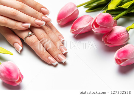 Woman showing french manicure and pink tulips on white background Woman showing french manicure and pink tulips on white background 127232558