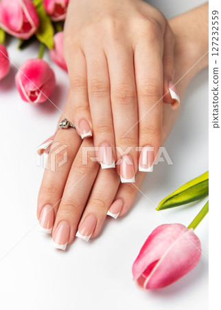 Woman showing french manicure and pink tulips on white background Woman showing french manicure and pink tulips on white background 127232559