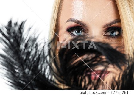 Woman portrait with partly covered her face with black feathers Woman portrait with partly covered her face with black feathers 127232611