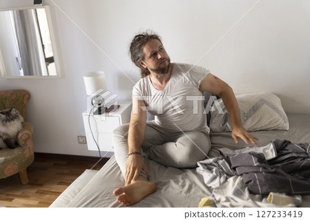 Man waking up and stretching legs on unmade bed Man waking up and stretching legs on unmade bed 127233419