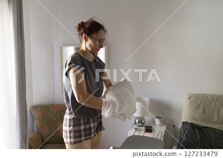 Housewife arranging pillowcase before ironing in bedroom Housewife arranging pillowcase before ironing in bedroom 127233479