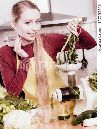 Woman in kitchen making vegetable smoothie juice 127233726