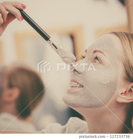 Woman applying with brush clay mud mask to her face Woman applying with brush clay mud mask to her face 127233736