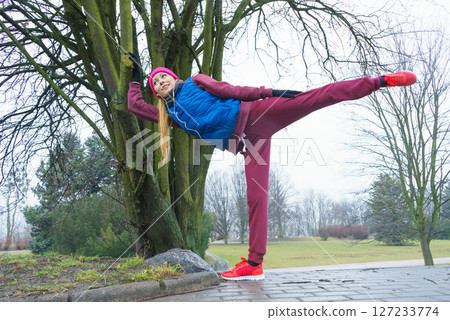 Woman wearing sportswear exercising outside during autumn 127233774
