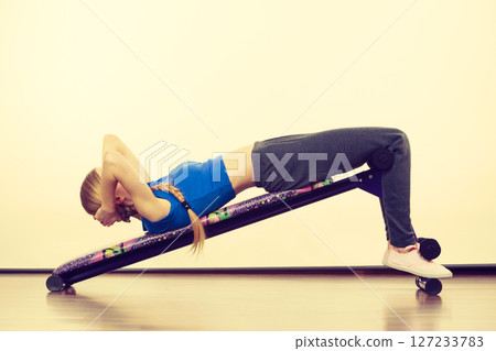 Woman training on bench for sit ups 127233783