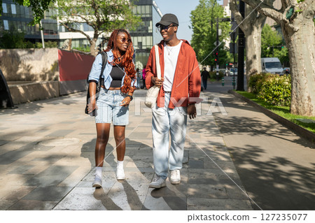 Joyful African American loving couple walking in city street guy makes girlfriend laugh. Joyful African American loving couple walking in city street guy makes girlfriend laugh. 127235077