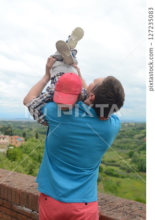 Father Lifting Son in Air with Scenic Landscape View Father Lifting Son in Air with Scenic Landscape View 127235083
