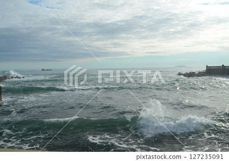 Coastal Waves Crashing Against Rocky Shoreline at Dusk 127235091